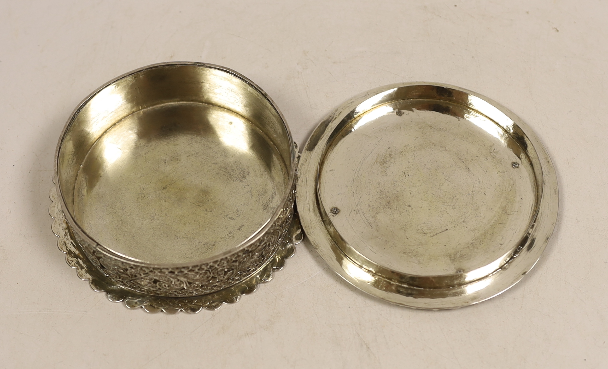 A continental white metal circular box and cover, with applied filigree decoration, diameter 11.2cm, 8.5oz.